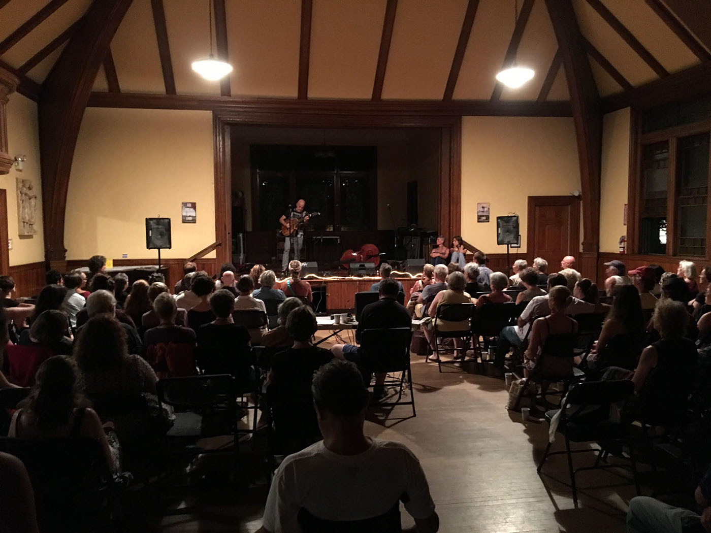 a musician performs on stage in the Main Hall as the audience looks on